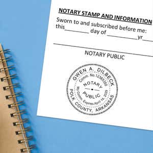 Arkansas notary stamp impression on white paper on a blue notebook.