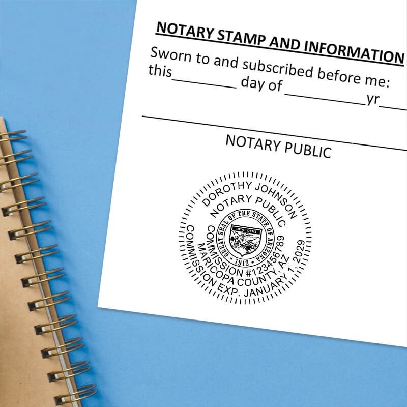 Arizona notary stamp impression on jurat form next to spiral notebook on blue background.