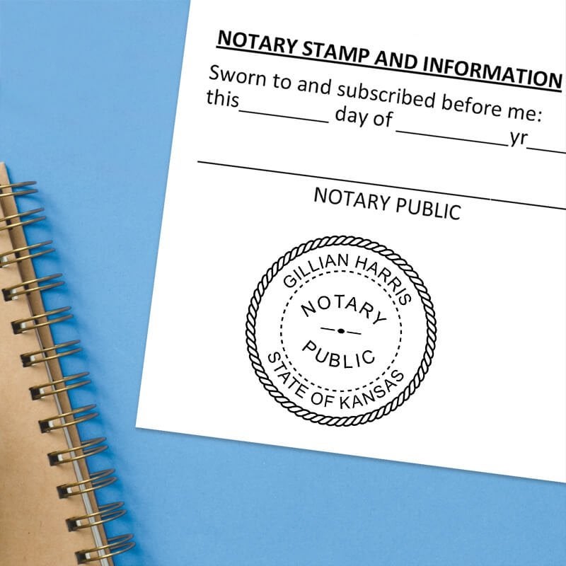 Kansas notary stamp impression on white paper on a blue notebook. 