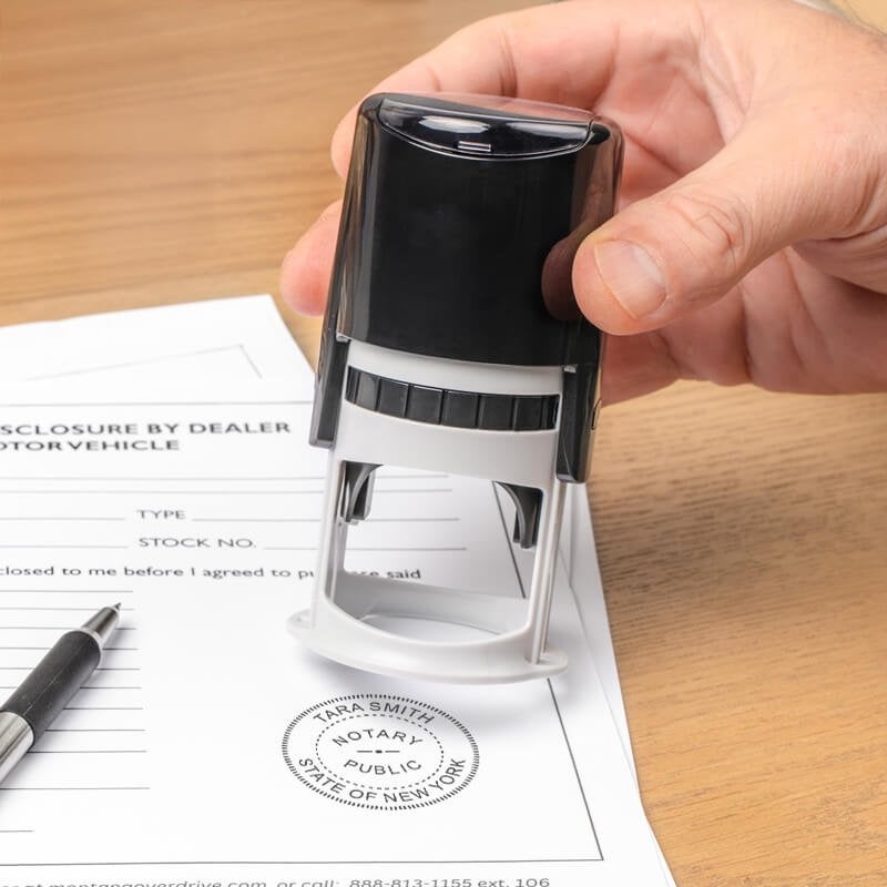 Applying Florida notary stamp to official document with pen nearby on wooden desk.