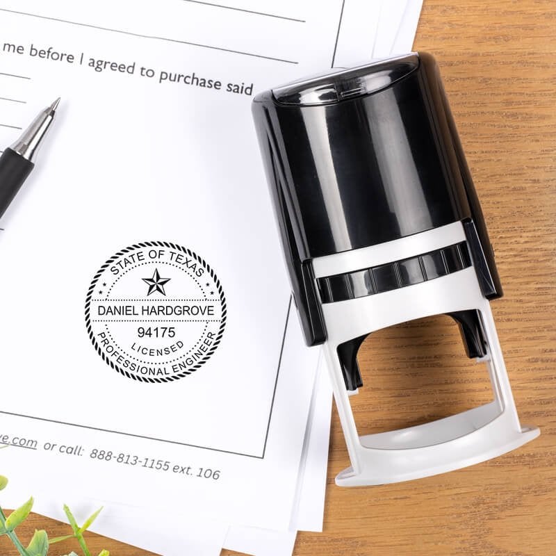 Texas engineer stamp on signed document with self-inking stamp and pen on wooden surface.