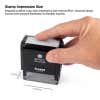 Hand pressing down on a Simply Stamps Trodat Printy 4913 self-inking stamp, with dimensions labeled as 7/8 inch by 2-3/8 inch to show impression size.