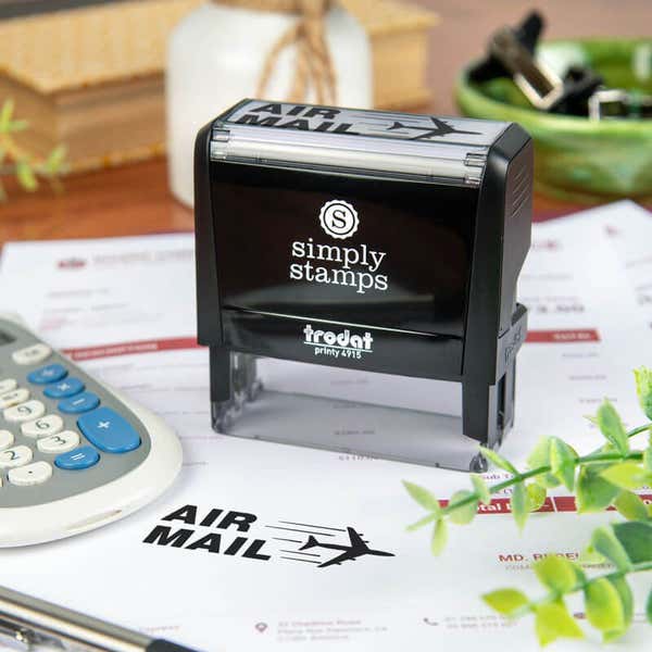 Simply Stamps Trodat Printy 4915 custom stamp shown stamping 'AIR MAIL' with airplane graphic on mailing documents, ideal for shipping, packaging, or business correspondence.