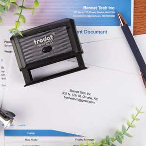 Trodat Printy 4918 stamp placed on printed documents from Bennet Tech Inc., used to apply a business return address in black ink.