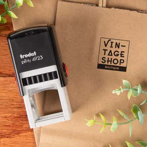 Trodat Printy 4923 custom stamp shown next to a kraft paper bag stamped with a boutique logo