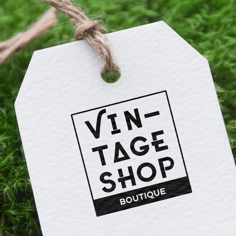 Close-up of a textured white hang tag stamped with the "Vintage Shop Boutique" logo in black ink