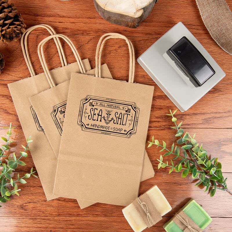 Extra Large MaxLight logo stamp being used to brand kraft paper bags with a vintage-style design