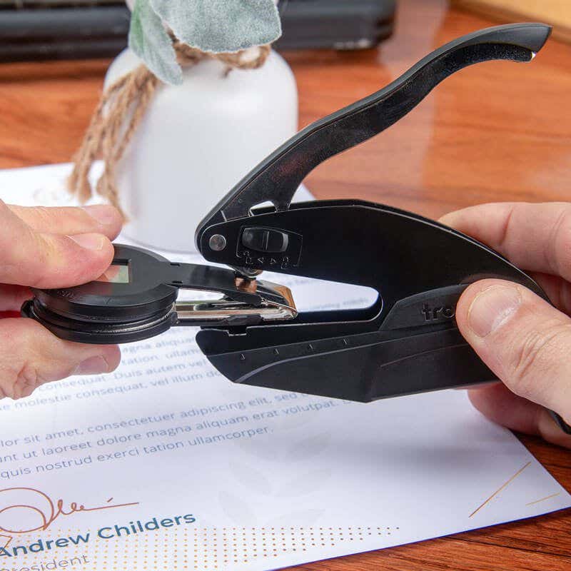 Hands removing the insert clip from a black pocket embosser to switch out custom embossing plates