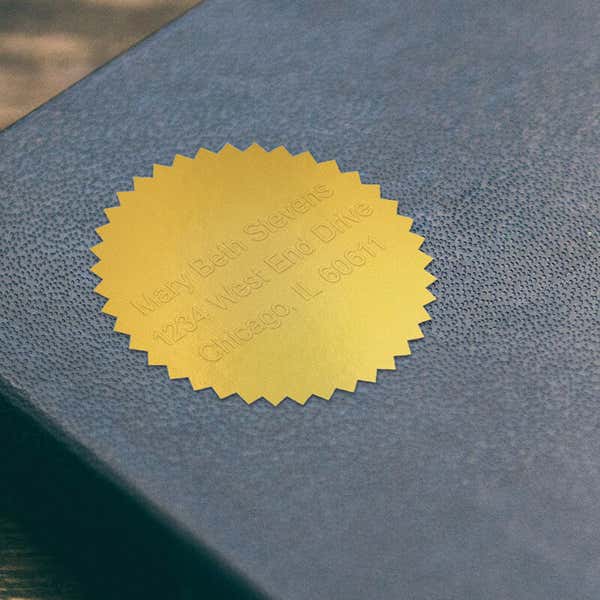 Example of Custom Text Embosser impression on gold foil sticker on blue book