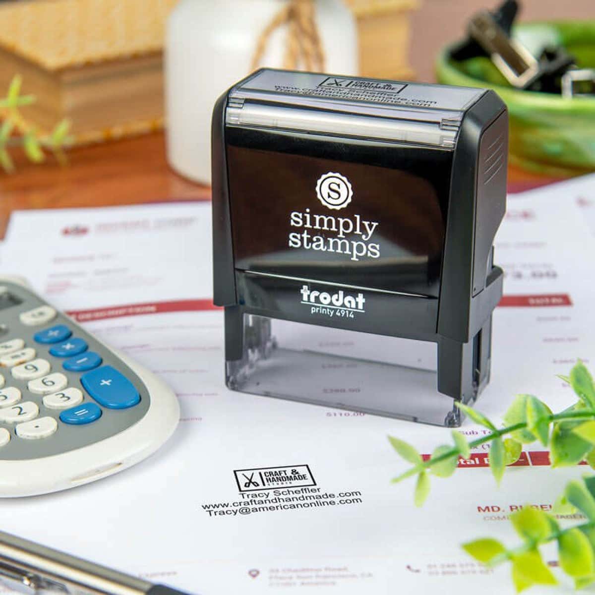 Simply Stamps self-inking stamp resting on a document that has been stamped with a business logo and informational text