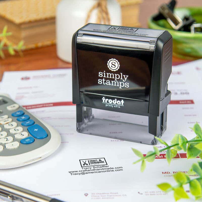 Simply Stamps self-inking stamp resting on a document that has been stamped with a business logo and informational text