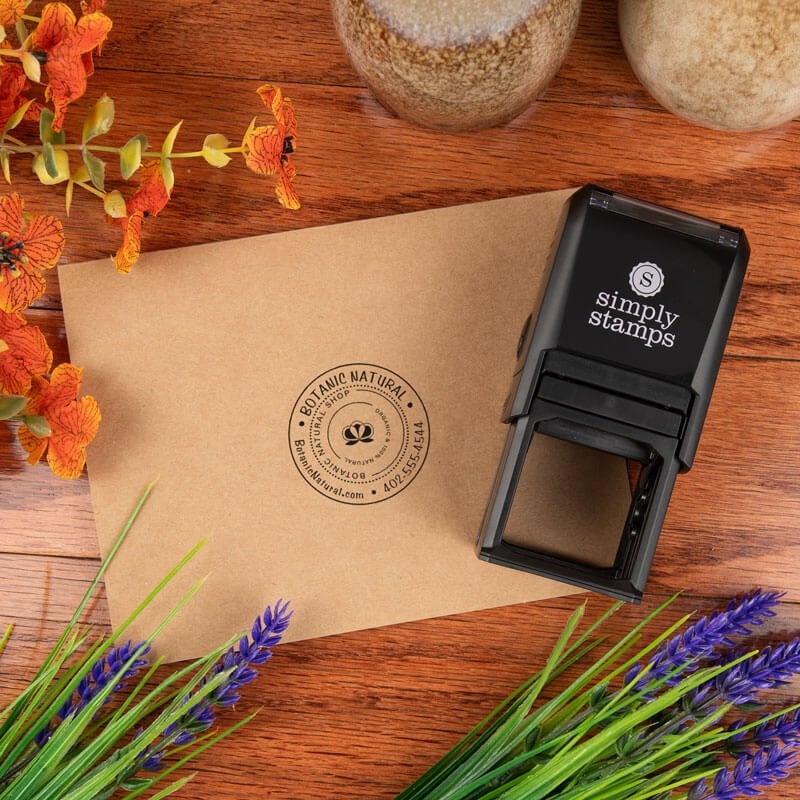 Self-inking stamp being used to stamp envelopes with a custom circular logo