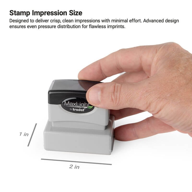 Hand pressing down on a MaxLight by Trodat stamp to show the 1 inch by 2 inch stamp impression size