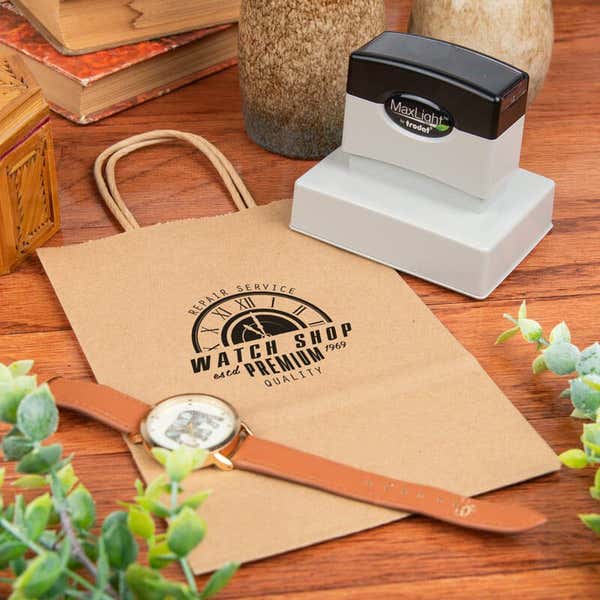 MaxLight stamp next to a paper gift bag that has been stamped with a custom design