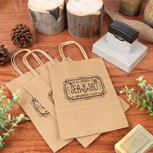 Large stamp next to a paper gift bag that has been stamped with a custom design