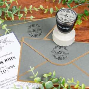 Pre-inked custom stamp used to personalize wedding envelopes with a floral Clara & John design, perfect for elegant event stationery and invitations."