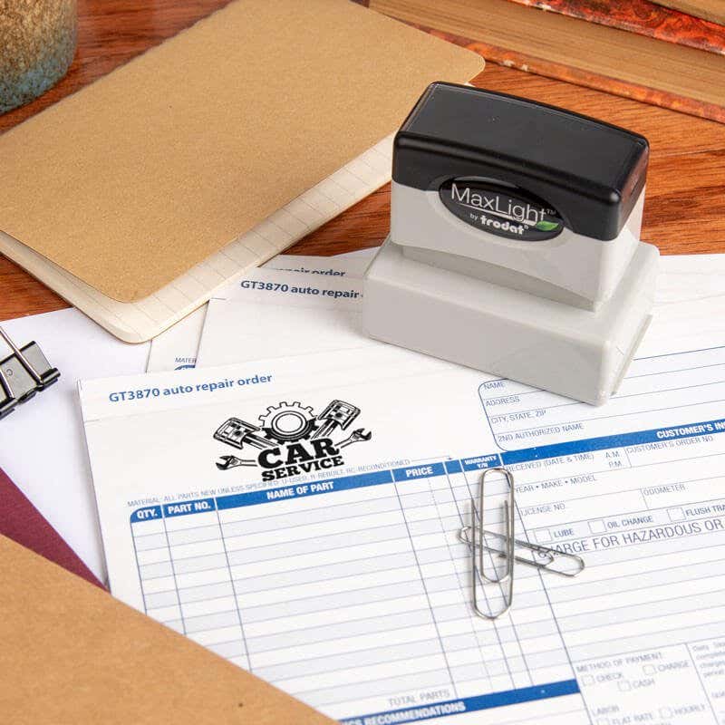 Custom round MaxLight stamp being used to mark a repair order with the word "PAID" in red