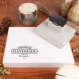 MaxLight pre-inked stamp resting on a white product box with a stamped “Premium Handmade” logo