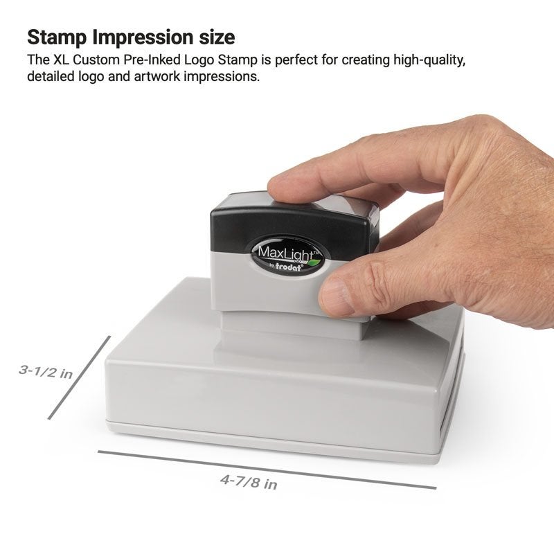 Hand holding a MaxLight by Trodat pre-inked stamp. The impression area measures 3-1/2" x 4-7/8"