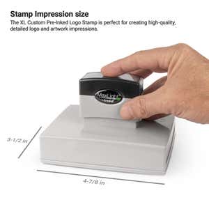Hand holding a MaxLight by Trodat pre-inked stamp. The impression area measures 3-1/2" x 4-7/8"