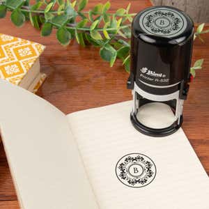 The Shiny R-532 stamp sits atop an open notebook, showcasing a custom monogrammed logo