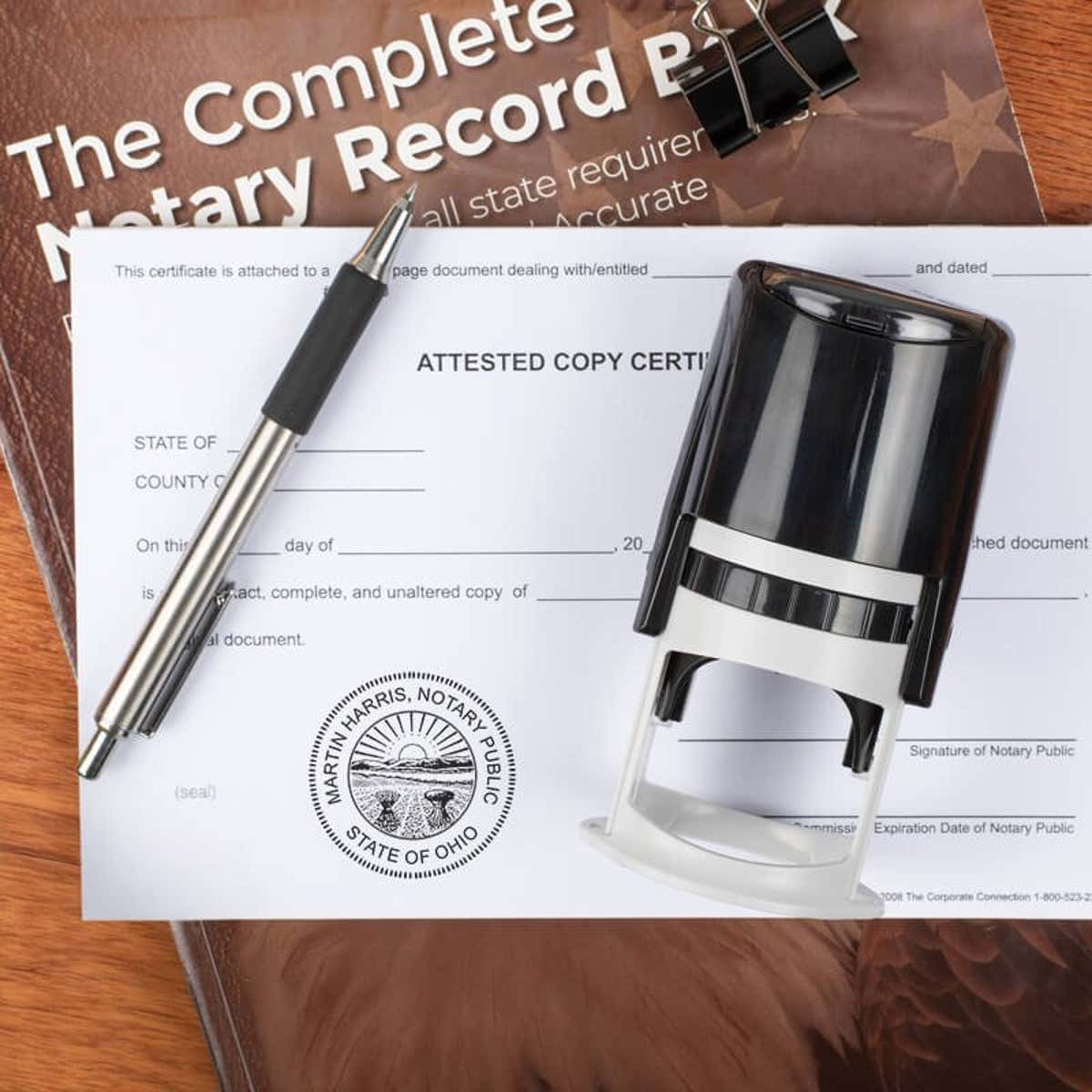 Ohio notary stamp on affidavit with pen and record book on wooden desk.