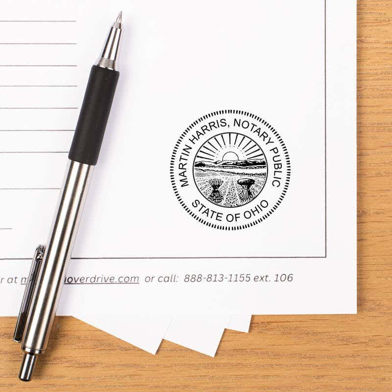 Ohio notary stamp impression on paper with pen on wood desk.