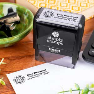 Trodat Printy 4914 self-inking address stamp customized with name and floral monogram, shown stamping a return address on an envelope