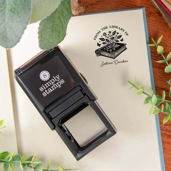 Flower library book stamp with self-inking stamp body on a book page