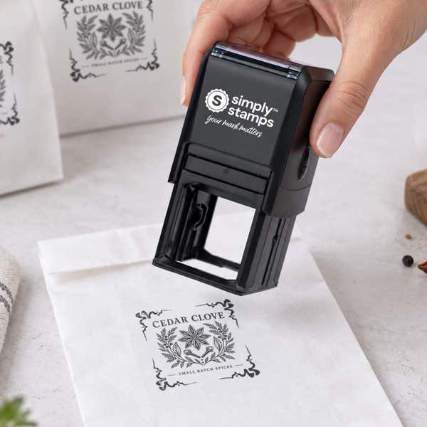 4 Corner Deco Border Logo Stamp resting beside a freshly stamped custom logo impression