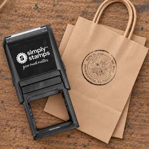 Broken Circle Round Logo Stamp resting beside a freshly stamped custom logo impression