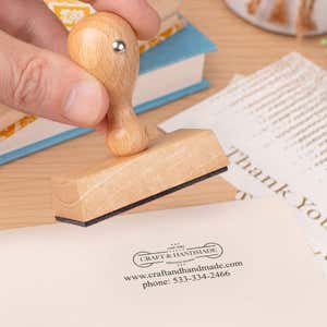 Custom 2 Line Rectangle Logo Hand Stamp in use, with a stamped logo impression on packaging