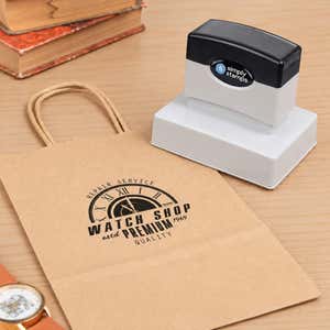 Medium 2-3/8" x 3-1/4" Custom Pre-Inked Logo Stamp resting beside a freshly stamped custom logo impression