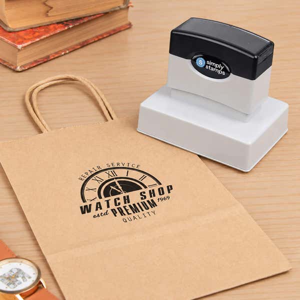 Medium 2-3/8" x 3-1/4" Custom Pre-Inked Logo Stamp resting beside a freshly stamped custom logo impression