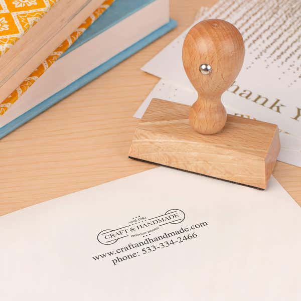 Custom 2 Line Rectangle Logo Hand Stamp in use, with a stamped logo impression on packaging (second view)