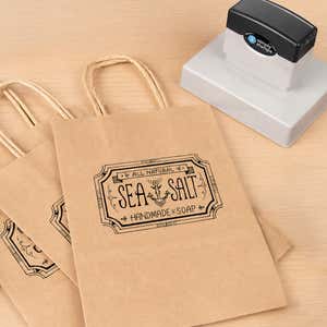 Large 3" x 4" Custom Pre-Inked Rectangular Logo Stamp resting beside a freshly stamped custom logo impression
