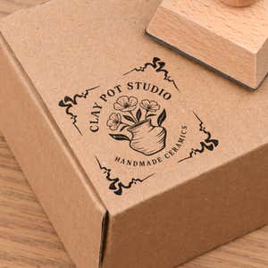 4 Corner Deco Border European Wood Handle Hand Stamp in use, with a stamped logo impression on packaging