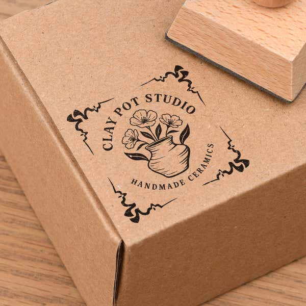 4 Corner Deco Border European Wood Handle Hand Stamp in use, with a stamped logo impression on packaging