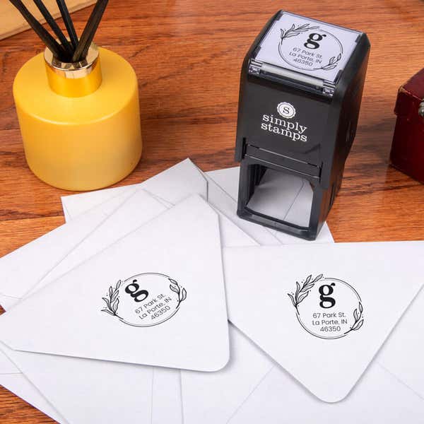 Elegant Botanical Monogram Address Stamp design impression on two envelopes next to self inking stamp body