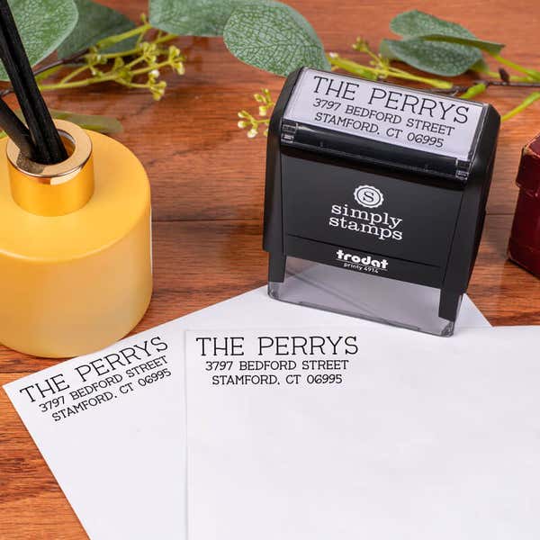 Humble Serif Custom Return Address Stamp design impression on two envelopes next to self inking stamp body