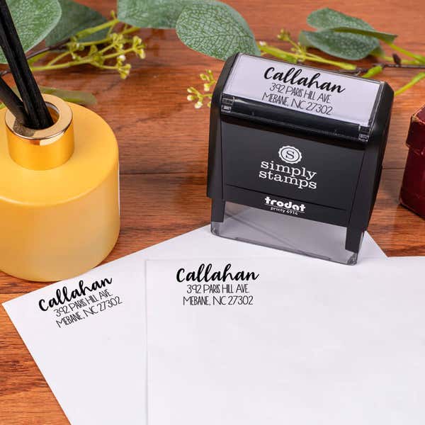 Fully Customizable Script Name Return Address Stamp design impression on two envelopes next to self inking stamp body