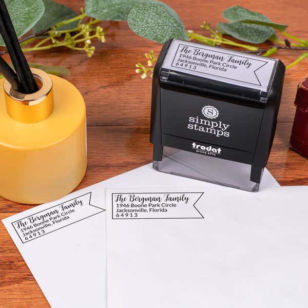 Bergman Fancy Border Address Stamp design impression on two envelopes next to self inking stamp body