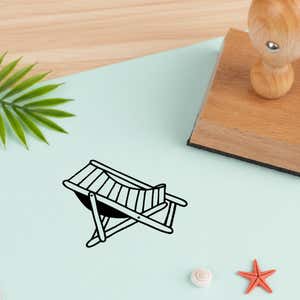 beach chair stamped in black on pale aqua cardstock beside a palm frond, a white seashell and a coral starfish