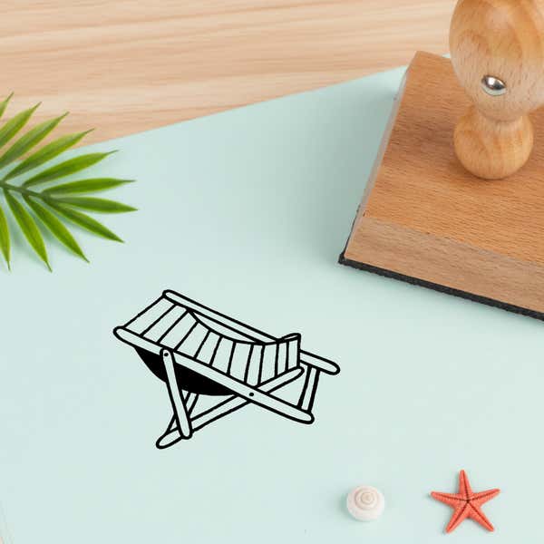 beach chair stamped in black on pale aqua cardstock beside a palm frond, a white seashell and a coral starfish