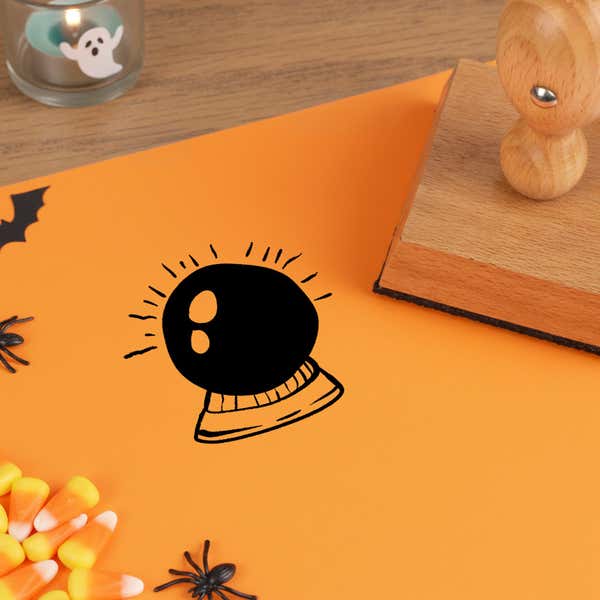 mystic crystal ball stamped in black on orange cardstock beside a wooden stamp, candy corn and a paper bat cutout