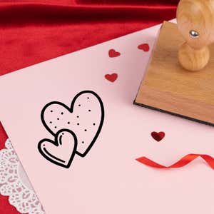 sweetheart double hearts stamped in black on pink cardstock with red heart confetti, ribbon, a lace doily and the stamp