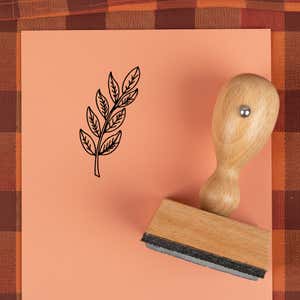 Leafy branch sprig stamped in black on peach cardstock on a plaid autumn cloth