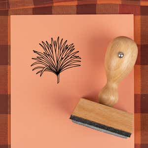 Fanned grass spray stamped in black on peach cardstock on a plaid autumn cloth