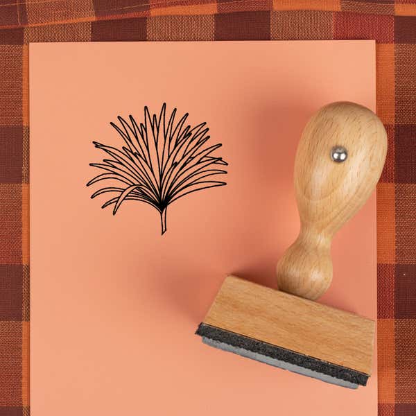 Fanned grass spray stamped in black on peach cardstock on a plaid autumn cloth