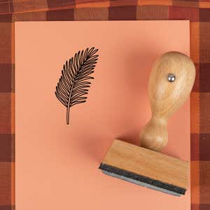 Feathered frond stamped in black on peach cardstock on a plaid autumn cloth
